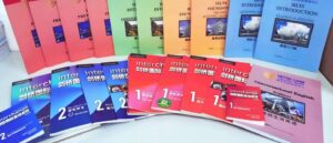 A collection of English language learning materials, including "Interchange" (剑桥国际) textbooks and workbooks (Student's Book, Workbook) in different levels (1, 2, 11) and editions, "IELTS Introduction Listening & Speaking" and "IELTS Introduction Reading & Writing" books, "Foundation English" books, and other unidentified books with titles in English and possibly Sinhala, arranged on a white surface in Sri Lanka. The books are published by Cambridge University Press and are likely used for English language education or IELTS preparation.